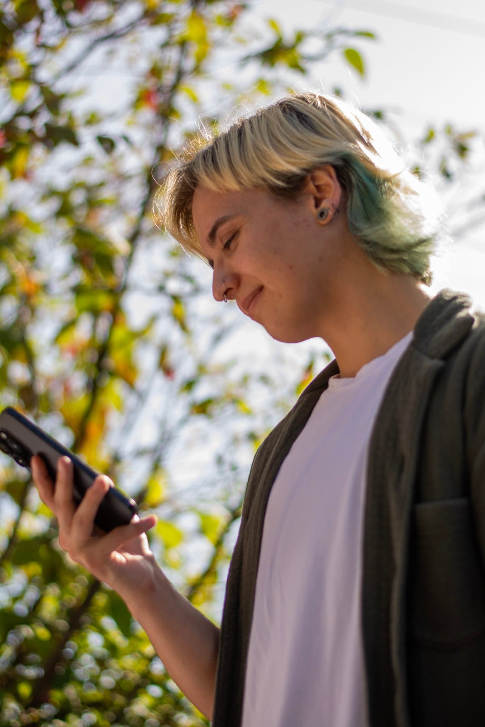 Person smiling at their phone outdoors